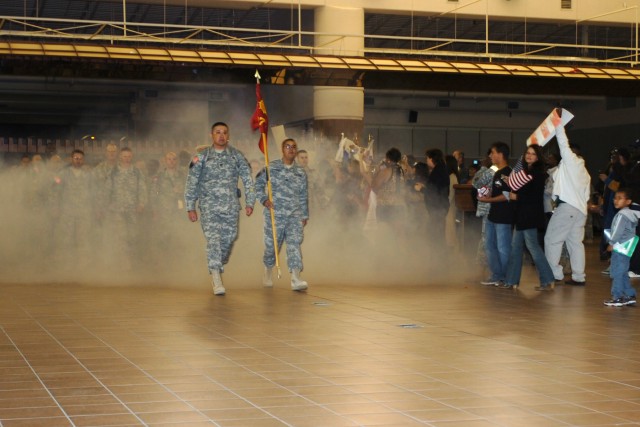 Family members cheer as members of the 377th Transportation Company, a part of the Fort Hood-based 180th Transportation Battalion, 15th Sustainment Brigade, emerge from the fog at their welcome home ceremony Nov. 14 at Fort Bliss' Biggs Army Airfield...