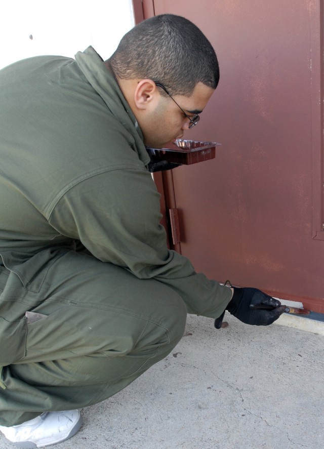 Spc. Patrick Ouzenne, a 418th Transportation Company, 180th Transportation Battalion, 15th Sustainment Brigade, cook, touches up worn patches of a door's paint at the Community Life Center of the military housing area Pershing Park as part of the pro...