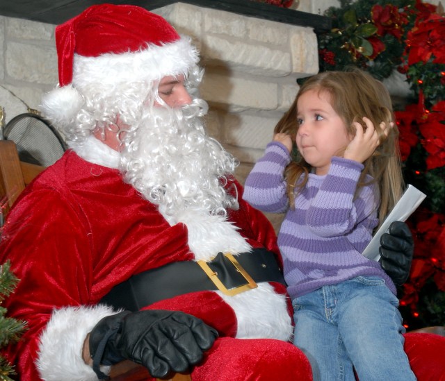 Lea Heald, 3, asks Pfc. Rob Floyd, Santa Claus and signal support systems specialist A Company, 15th Special Troops Battalion, 15th Sustainment Brigade for a video game for Christmas at a 15th STB Family Readiness Group Christmas open house event...