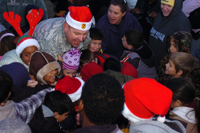 Col. Larry Phelps, commander of the 15th Sustainment Brigade, 13th Sustainment Command (Expeditionary), gets a little bit of help throwing the switch to light the brigade's Christmas tree Dec. 5 at the unit's junior family readiness group tree...