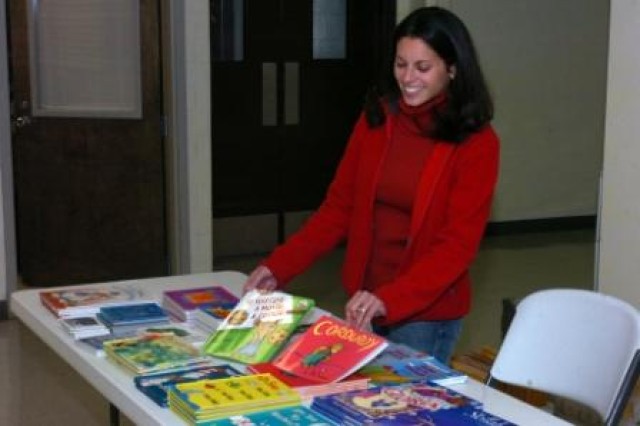 Lucy Limon, wife of a deployed Soldier and United Service Organization's volunteer, showcases books available as part of the USO's United Through Reading program for Soldiers preparing to deploy. Soldiers can read the books aloud and have their sessi...