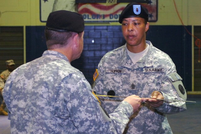 Lt. Col. Mark Paget, the commander of the 180th Transportation Battalion, 15th Sustainment Brigade, 13th Sustainment Command (Expeditionary), passes the traditional Noncommissioned Officer Saber to Command Sgt. Maj. Vickie Hopson, charging her with r...