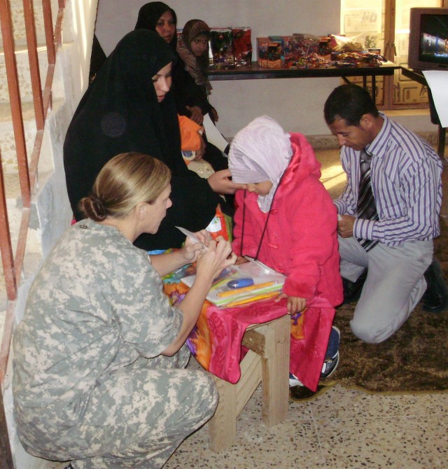 Capt. Lori August, 27th BSB, 4th BCT, 1st Cav. Div., and a native of Austin, Texas, gives an Iraqi student school supplies donated by families in the U.S.  Soldiers on COB Adder gave these supplies to the children after administering hearing exams...