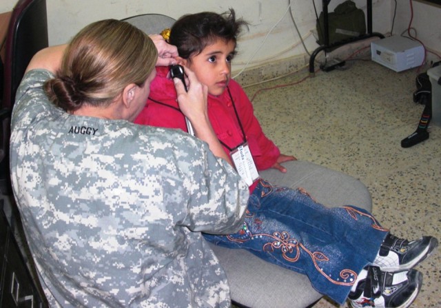 Capt. Lori August, 27th BSB, 4th BCT, 1st Cav. Div., and a native of Austin, Texas, inspects an Iraqi child's ear for abnormalities or inconsistencies.  Each child also took a hearing exam; the results were compiled into a detailed profile for each i...