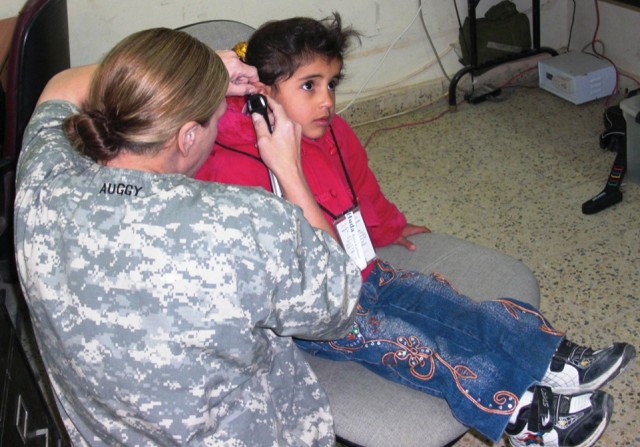 Capt. Lori August, 27th BSB, 4th BCT, 1st Cav. Div., and a native of Austin, Texas, inspects an Iraqi child's ear for abnormalities or inconsistencies.  Each child also took a hearing exam; the results were compiled into a detailed profile for...