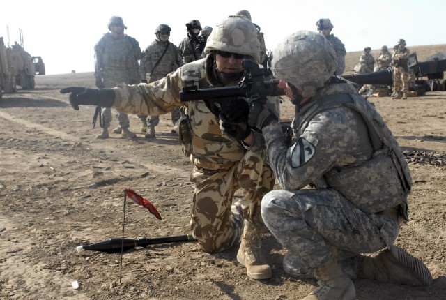 A Romanian soldier, assigned to the 341st Romanian Inf. Bn. instructs Spc. Justin Dreyer, assigned to the 4th Special Troops Bn., 4th BCT, 1st Cav. Div., how to fire a rocket-propelled grenade launcher during a cross-training event at the Bardia...