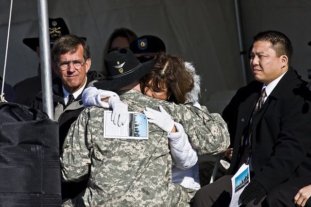 During the dedication ceremony of the 1st Air Cavalry Brigade, 1st Cavalry Division, headquarters buildings, Chief Warrant Officer 2 Jacob Gaston embraces Jasmine Crowl, mother of Chief Warrant Officer 3 Cornell Chao, with son Raymond Chao (right)...