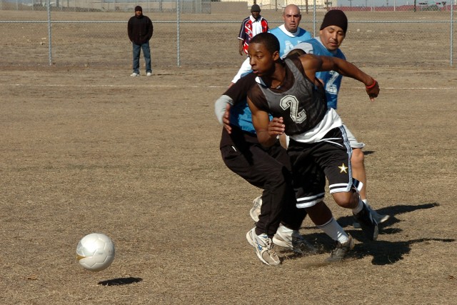 Spc. Desean Durham, with the Headquarters and Headquarters Company, Special Troops Battalion, 15th Sustainment Brigade, 13th Sustainment Command (Expeditionary), plays the ball past opponents of the 263rd Maintenance Company, Special Troops...