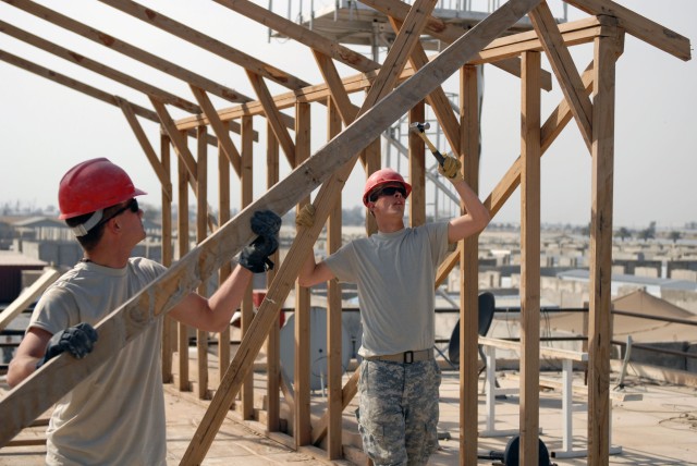 CAMP VICTORY, Iraq - Pvt. Curtis Nordby, (right) of Pineville, La., and Pvt. Chip Normand, of  Marksfield, La., use teamwork to dismantle a rotting shade structure on top of the 225th Engineer Brigade headquarters overlooking Camp Victory, Baghdad...