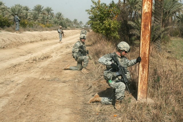 ISTAQLAL, Iraq - Sgt. George Davis (foreground), of Buena Vista, Colo., maintains security during a combined cache operation Feb. 7 with their Iraqi partners assigned to the 2nd Brigade, 1st Iraqi National Police Division, in the Rashidiyah Nahia, no...