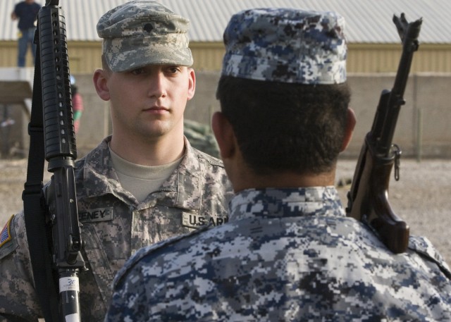 CAMP LIBERTY, Iraq - Spc. Lucas Sweeney (left), of Rapids, Wis., 1st Cavalry Division Honor Guard, Multi-National Division-Baghdad, performs drills with Matham Hussein Ali, 1st National Division, on Camp Liberty Feb. 8. The two practice rifle...