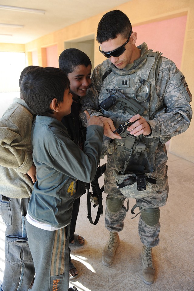 BAGHDAD - Capt. Agustin Dominguez, a fire support officer assigned to 2nd Battalion, 505th Parachute Infantry Regiment, 3rd Brigade Combat Team, 82nd Airborne Division, Multi-National Division-Baghdad , shows Iraqi children his camera screen after...