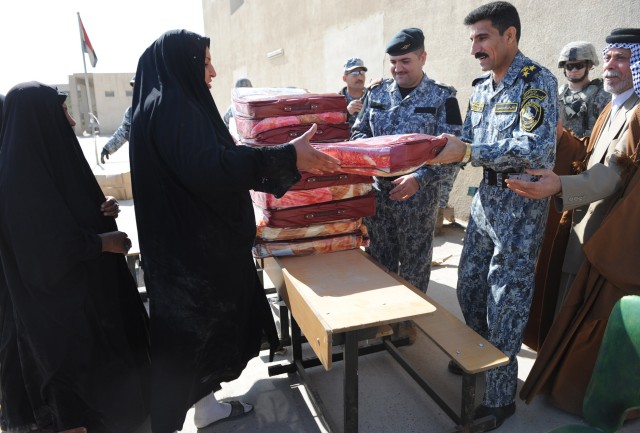 BAGHDAD - Iraqi Brig. Gen. Ali Ibraheem Dabown, commander of the 8th National Police Brigade, 2nd NP Division, gives a wool blanket to a woman during a humanitarian drive Feb. 4 at a school in the New Baghdad district of eastern Baghdad. More than...
