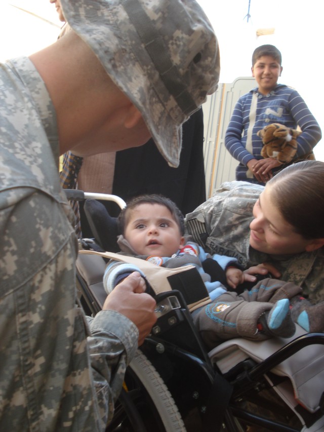 BAGHDAD- Spc. David Helfman (left) , of Coloma, Mich., and Spc. Keisha Barajas, of Portage, Ind., both with Civil Affairs Team 31 of the 2nd Brigade Combat Team, 1st Armored Division, fit Ahmad into his pediatric wheelchair Feb.7. Ahmad was one of th...