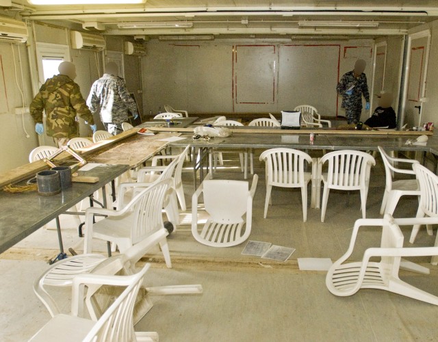 An Iraqi police officer questions a detainee while two Iraqi Police and Army intelligence specialists begin searching for clues in a room notionally used for bomb making in a training environment at Camp Dhi Qar, the 10th Iraqi Army Division's headqu...