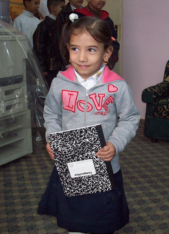 SADR CITY, Iraq - An Iraqi girl smiles after receiving a new notebook from Soldiers assigned to the 1st Battalion, 6th Infantry Regiment, during a school supply distribution mission at the Al Aqbas Elementary school Feb. 9 in the Sadr City...