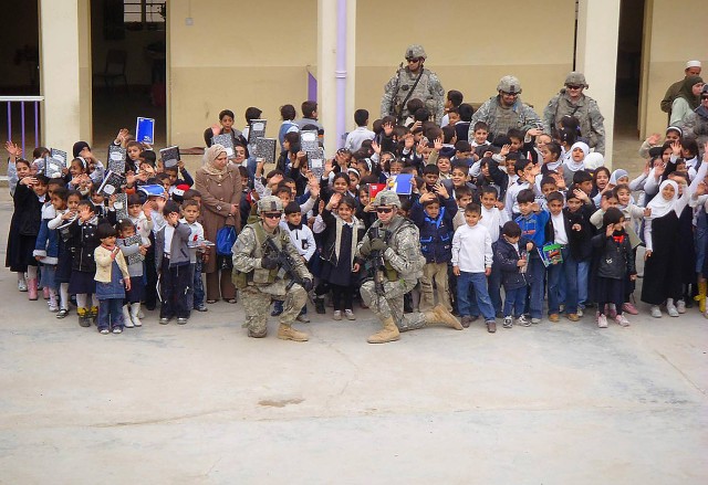 SADR CITY, Iraq - Students of the Al Aqbas Elementary School smile and wave during a group picture at the school's courtyard Feb. 9 in the Sadr City district of eastern Baghdad. Soldiers assigned to the 1st Battalion, 6th Infantry Regiment,...