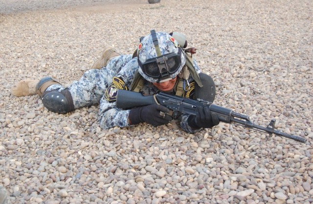 JOINT SECURITY STATION ISTAQLAL, Iraq - An National Police officer assigned to 2nd Brigade, 1st NP Division, positions himself in a prone fighting position after dismounting an UH-60 helicopter, Feb. 15 at Joint Security Station Istaqlal.  NP officer...