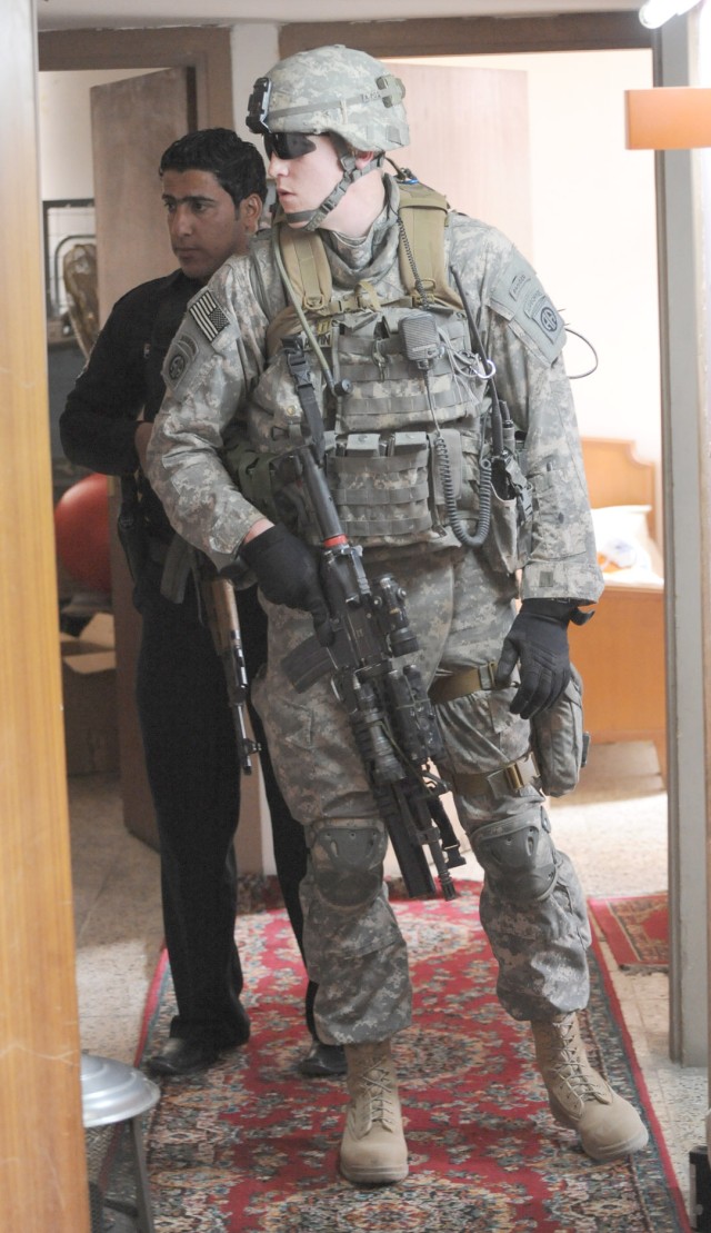 JOINT SECURITY STATION MUTHANA, Iraq -Sgt. Nathan Martin, a native of Statham, Ga., a team leader assigned to Troop B, 5th Squadron, 73rd Cavalry Regiment, 3rd Brigade Combat Team, 82nd Airborne Division and an Iraqi Police officer look inside a room...