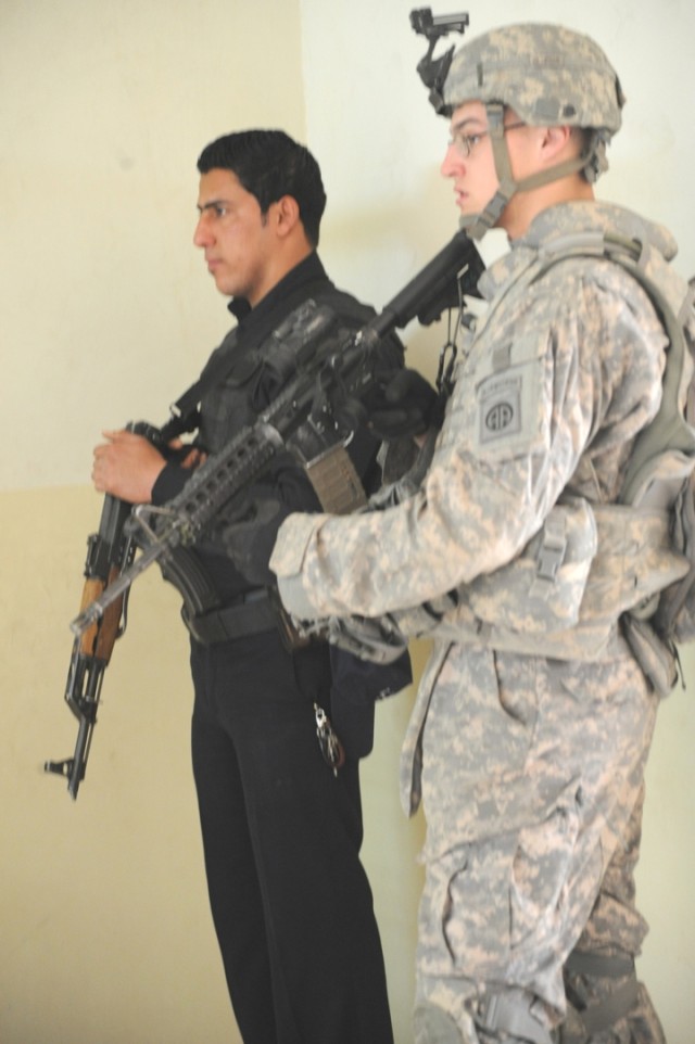 JOINT SECURITY STATION MUTHANA, Iraq - Pfc. William Weigold, of New York City, an infantryman assigned to Troop B, 5th Squadron, 73rd Cavalry Regiment, 3rd Brigade Combat Team, 82nd Airborne Division, and an Iraqi Police officer secure a hallway insi...