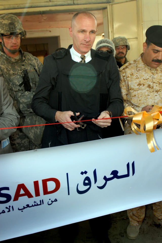 BAGHDAD - Thomas Delaney (center), deputy mission director, United States Agency for International Development, Iraq, prepares to cut the ceremonial ribbon signifying the re-opening of the Shawaka Fish Market in the Karkh district of northwest...
