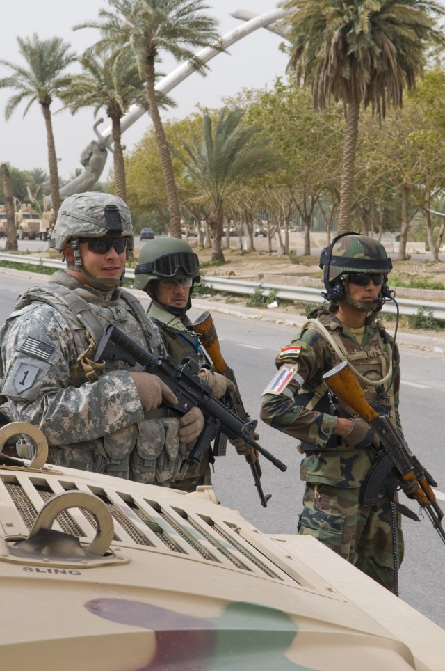 BAGHDAD -Sgt. Derrick Junge (left), 1st Battalion, 7th Field Artillery Regiment,  2nd Heavy Brigade Combat Team, 1st Infantry Division, Multi-National Division-Baghdad, observes an Iraqi Army platoon conducting  traffic control point operations in...