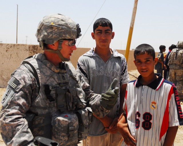 BAGHDAD - Sgt. 1st Class Donald Johnson, from Barron, Wis., the electronic warfare officer of the 2nd Brigade Combat Team, 1st Armored Division, Multi-National Division-Baghdad, talks with local Iraqi kids while on a patrol May 31, 2008.  His 22-year...