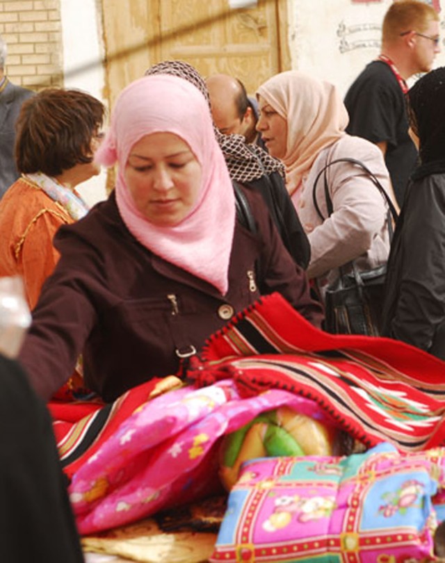 BAGHDAD- A local Iraqi woman from the Mahmudiyah Qada arranges her table of merchandise during the Women's Bazaar hosted by Task Force 1st Combined Arms Battalion, 63rd Armor Regiment FOB Mahmudiyah Feb 17. The Women's Bazaar allowed the local women ...