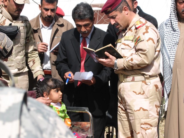 Baghdad - Iraqi Army Lt. Col. Tahseen (right), commander of the 2nd Battalion, 55th Brigade, 17th IA Division, and Saad Hamid Schnater, manager of the Adwaniyah Clinic, donate a wheelchair Feb. 18 to the family of a young girl with a nerve...