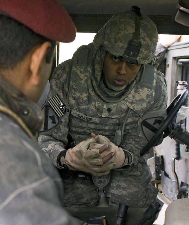 Spc. Abdurahim Sharif, a mechanic with the Forward Support Company, 3rd Battalion, 8th Cavalry Regiment, 3rd Heavy Brigade Combat Team, 1st Cavalry Division attached to 25th Infantry Division, Multi National Division - North, talks with Pvt. Omar...
