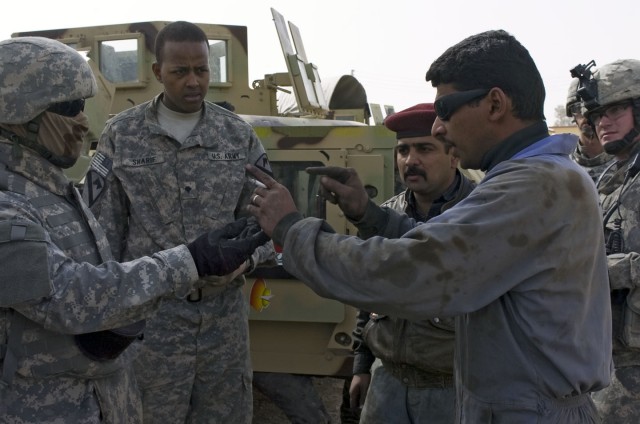 Spc. Abdurahim Sharif, a mechanic with the Forward Support Company, 3rd Battalion, 8th Cavalry Regiment, 3rd Heavy Brigade Combat Team, 1st Cavalry Division attached to 25th Infantry Division, Multi National Division - North talks with two of his...