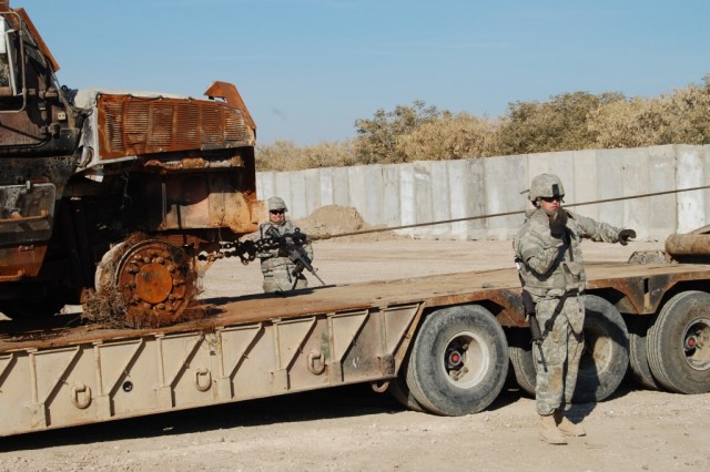CAMP LIBERTY, Iraq - Combat mechanic, Spc. Scott Monroe of Gulfport, Miss., with the 890th Engineer Battalion, uses hand signals to back a wrecker up so that a battle-damaged vehicle can be repositioned onto a trailer during recovery training at...