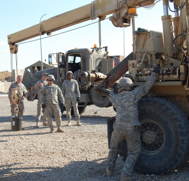 CAMP LIBERTY, Iraq - Spc. Randall Waltman (right), a native of Biloxi, Miss. and a mechanic with the 890th Engineer Battalion, practices the operation of a crane at the 890th Eng. Bn. motor pool as instructors and class members watch during...