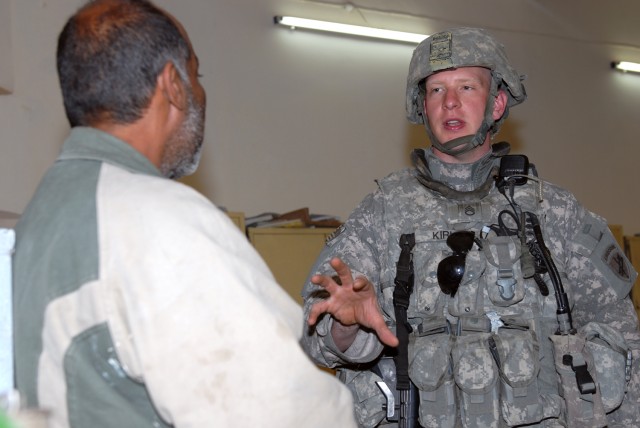 BAGHDAD - Staff Sgt. David Kirk, a civil affairs specialist assigned to the 401st Civil Affairs Battalion, 3rd Brigade Combat Team, 82nd Airborne Division, speaks with the caretaker of a school under refurbishment in the Saadoun neighborhood in easte...