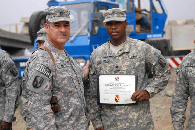 CAMP LIBERTY, Iraq - Gulfport Miss., native Spc. Calvin Coleman, a member of Company A, 890th Engineer Battalion, 225th Engineer Brigade, 1st Cavalry Division, Multi-National Division-Baghdad, receives a certificate of achievement from Command...