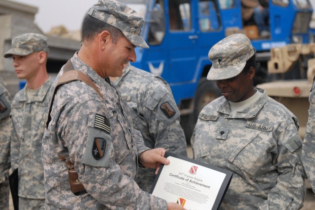 CAMP LIBERTY, Iraq - Gulfport Miss., native Spc. Susie Fautner, a member of Company A, 890th Engineer Battalion, 225th Engineer Brigade, 1st Cavalry Division, Multi-National Division-Baghdad, receives a certificate of achievement from Command Sgt....