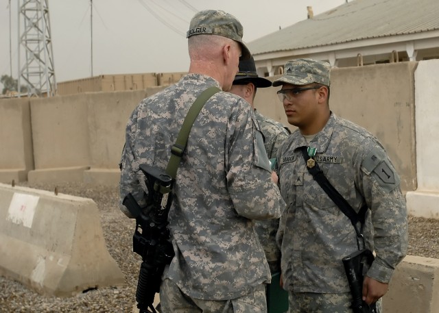 BAGHDAD - Cpl. Irving Aragon (right), 5th Squadron, 4th Cavalry Regiment, 2nd Heavy Brigade Combat Team, 1st Infantry Division, Multi-National Division-Baghdad is presented with the Army Commendation medal by Maj. Gen Daniel Bolger, commander,...