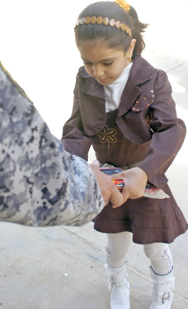 BAGHDAD- An Iraqi girl receives a variety of school supplies from a National Police officer during a distribution event Feb. 25 at the Shana and Shorwq Kindergarten in the Karada neighborhood in Baghdad. Her kindergarten was one of two schools to rec...