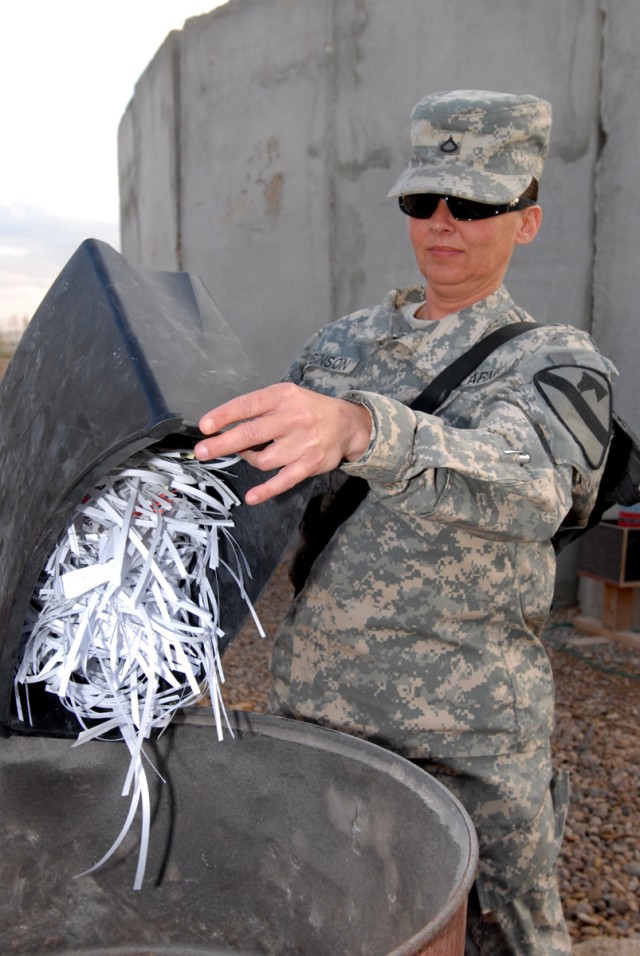 CAMP LIBERTY, Iraq - Pfc. Rose Robinson, an orderly room clerk, Company A, Division Special Troops Battalion, 1st Cavalry Division, fills burn barrels with shredded documents prior to setting them ablaze. Multi-National Division-Baghdad policy requir...