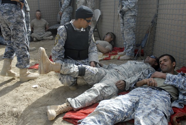 An Iraqi Policeman, from the Muthana Tactical Security Unit in southern Iraq, provides combat casualty care to an American Soldier who is role playing as an injured detainee during a two-week training exercise near Contingency Operating Base Adder, I...