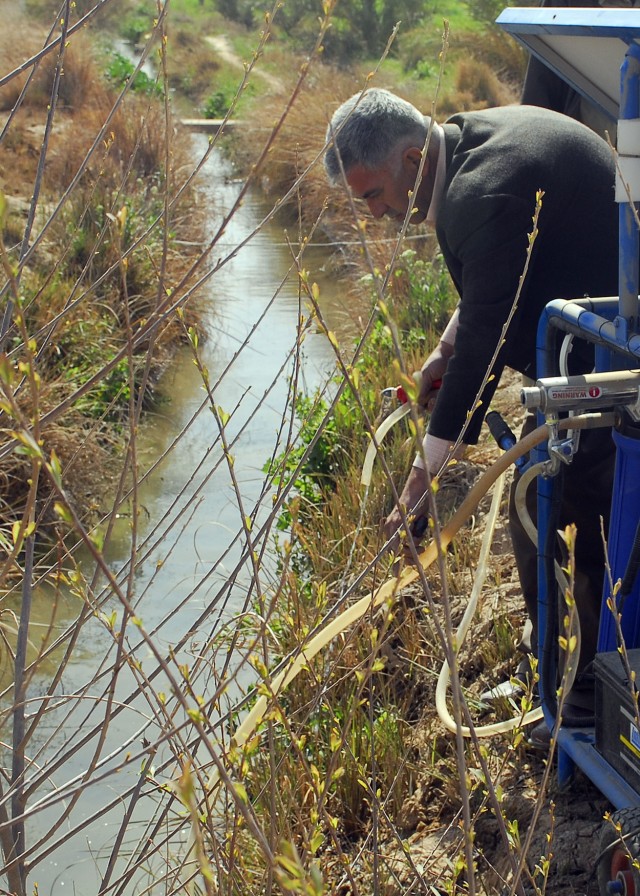 LUTIFIYAH, Iraq - Nadhel, an Iraqi engineer, places a tube into a water canal to bring water into a solar powered water purifier during a ceremony attended by local sheiks, villagers and Soldiers of the 1st Combined Arms Battalion, 63rd Armor...