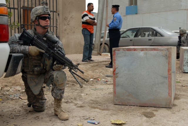 BAGHDAD - Spc. Warren Phillips, an M-249 Squad Automatic Weapon gunner, assigned to Troop B, 5th Squadron, 73rd Cavalry Regiment, 3rd Brigade Combat Team, 82nd Airborne Division, kneels while pulling security as his Iraqi Security Force partners...