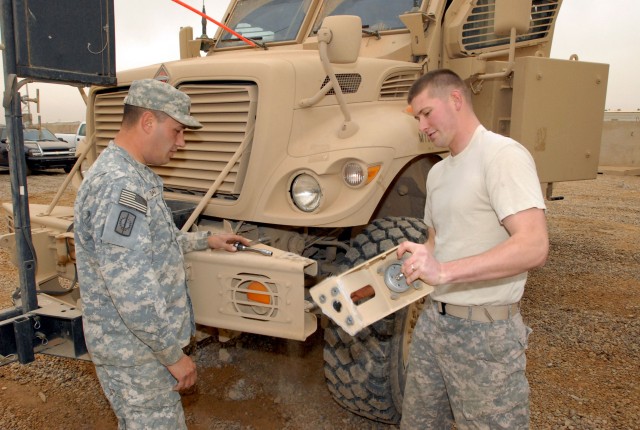 CAMP LIBERTY - Spc.  Mark Davis (left) an Audobon, N.J. native, and Sgt. Neil Baker (right) a Mancelona, Mich. native, both serving with the 8th Military Police Brigade, Multi-National Division-Baghdad, prepare to install a dual-wire mitigation...