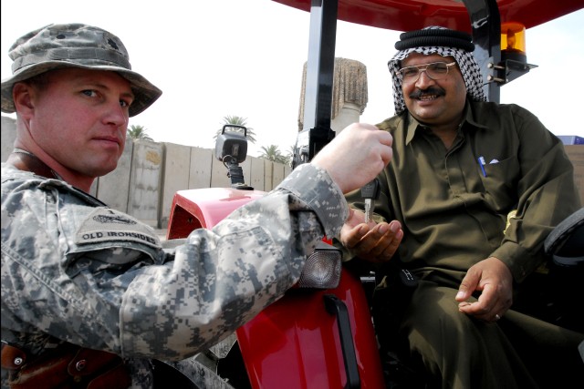 BAGHDAD- Lt. Col.  Michael Mammay, from Merrimark, N.H., commander, Task Force 4th Battalion, 27th Field Artillery hands the keys to the new ArmaTrac 602 tractor to Sheik Musa, a local leader in the Lutifiyah Nahia, during a ceremony held at...