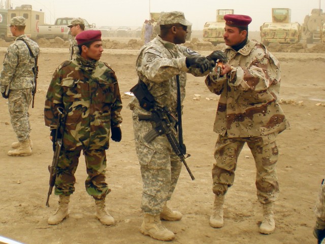 An American Soldier, assigned to the 5th Battalion, 82nd Field Artillery Regiment, 4th Brigade Combat Team, 1st Cavalry Division, assists an Iraqi Soldier from the 3rd Battalion, 41st Iraqi Army Brigade in a reflexive fire exercise during a joint...