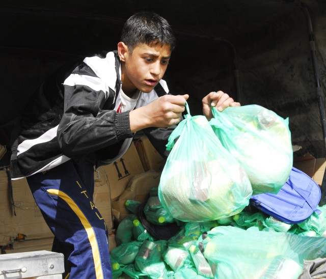 BAGHDAD - An Iraqi boy from the village of Jari, south of Baghdad, helps unload supplies March 6 that were provided by the 445th Civil Affairs Team, which is attached to Company C, 1st Combined Arms Battalion, 63rd Armor Regiment. The MND-B...