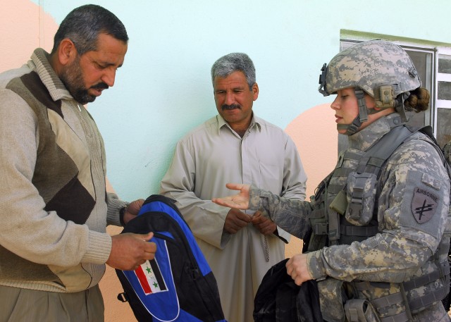 BAGHDAD - Portage, Ind. native Spc. Keisha Barajas, Civil Affairs Team 31, 1st Combined Arms Battalion 63rd Armor Regiment, hands a teacher a bag of school supplies during the grand re-opening of Almuwifikia School in Lutifiyah, Mahmudiyah Qada March...