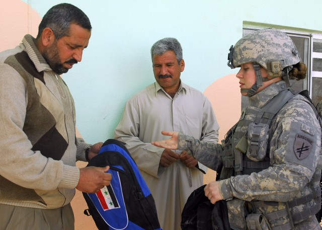 BAGHDAD - Portage, Ind. native Spc. Keisha Barajas, Civil Affairs Team 31, 1st Combined Arms Battalion 63rd Armor Regiment, hands a teacher a bag of school supplies during the grand re-opening of Almuwifikia School in Lutifiyah, Mahmudiyah Qada...