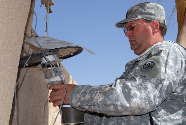 VICTORY BASE COMPLEX, Iraq - Capt. Michael Klaus, with 1848th Medical Detachment's preventative medicine section, removes the collecting unit from a Center for Disease Control miniature light trap. The trap catches  mosquitoes, sand flies and other f...