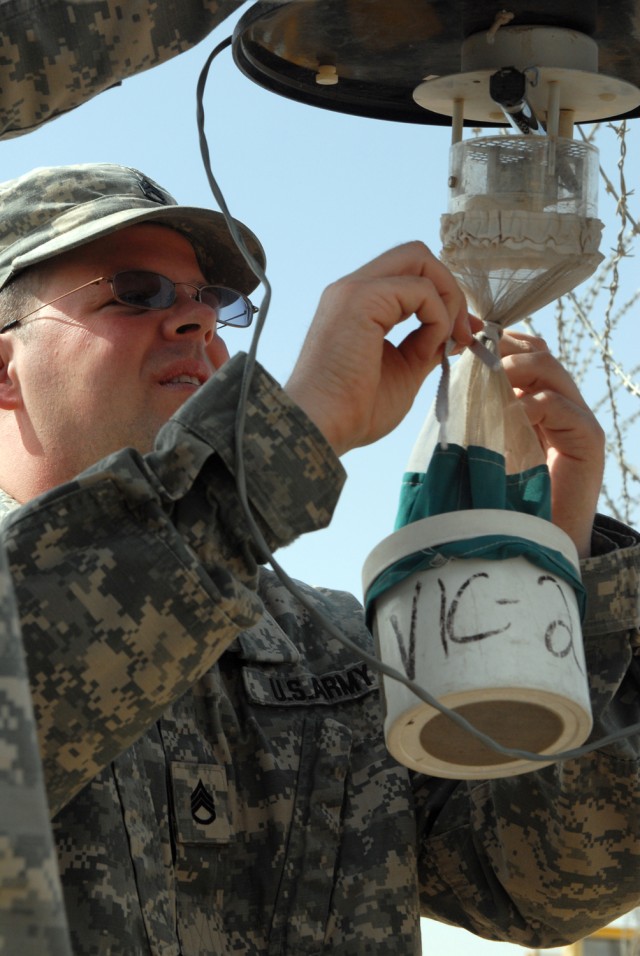 VICTORY BASE COMPLEX, Iraq -Staff Sgt. Seth Odette, 1848th Medical Detachment's preventative medicine section, removes the collecting unit from a Center for Disease Control miniature light trap. The trap uses an ultraviolet light and a small fan to t...